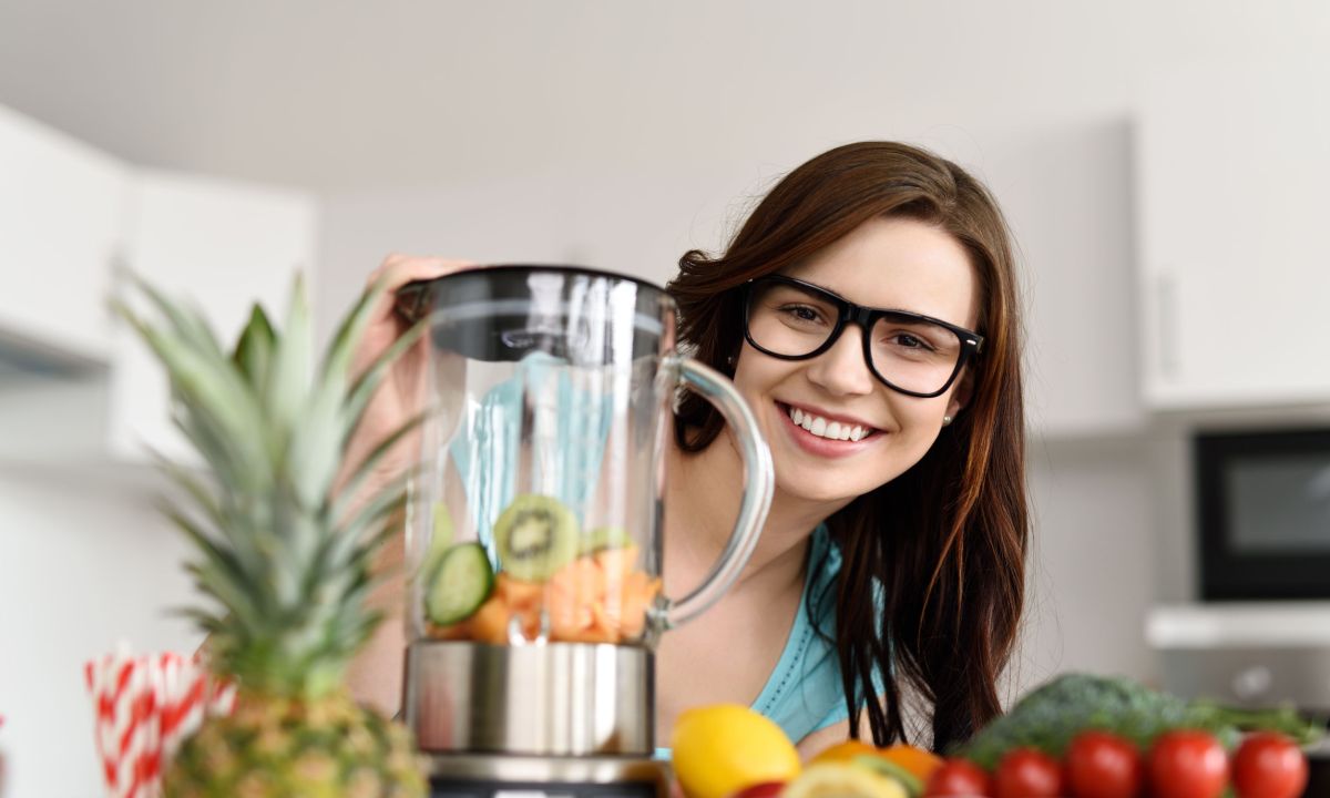 A woman preparing a meal using a blender.