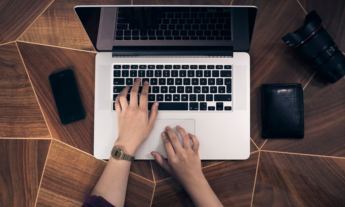 Person's hands resting on a laptop.
