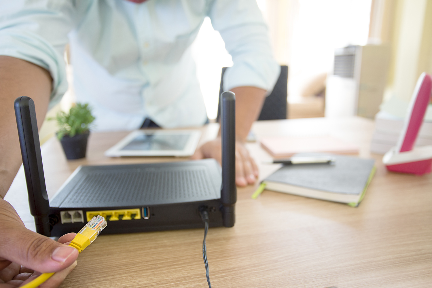 Plugging an Ethernet cable into the back of a Wi-Fi router.