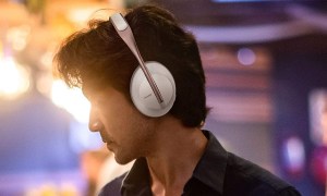 A man wearing Bose 700 headphones with a moody background.