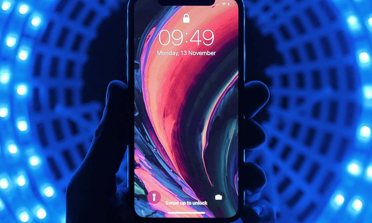 iPhone showing Lock Screen held against a dark background with a ring of lights.