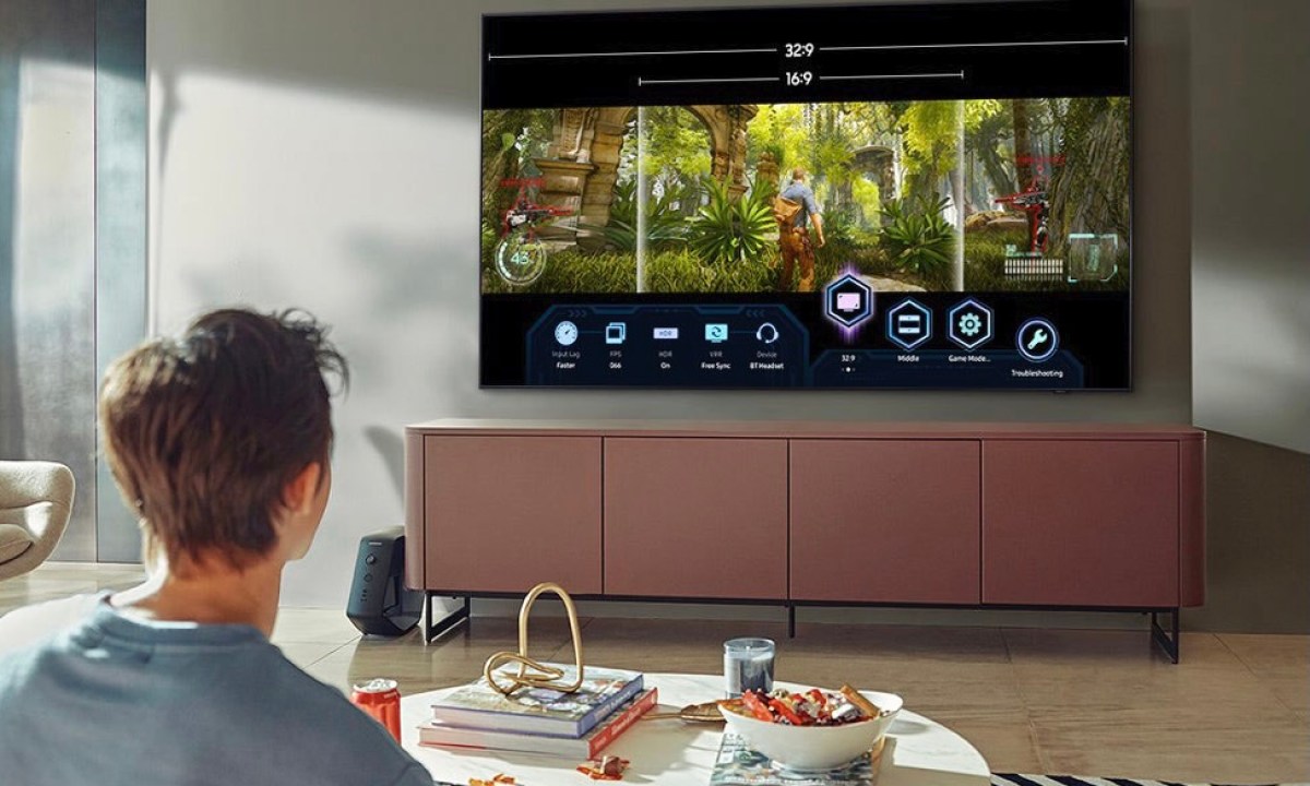 A man watching the Samsung 75-inch Q84A in his living room.
