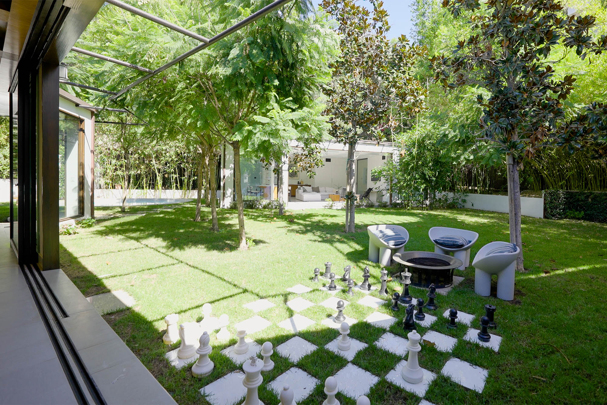A grassy backyard that has a life-sized chess game.