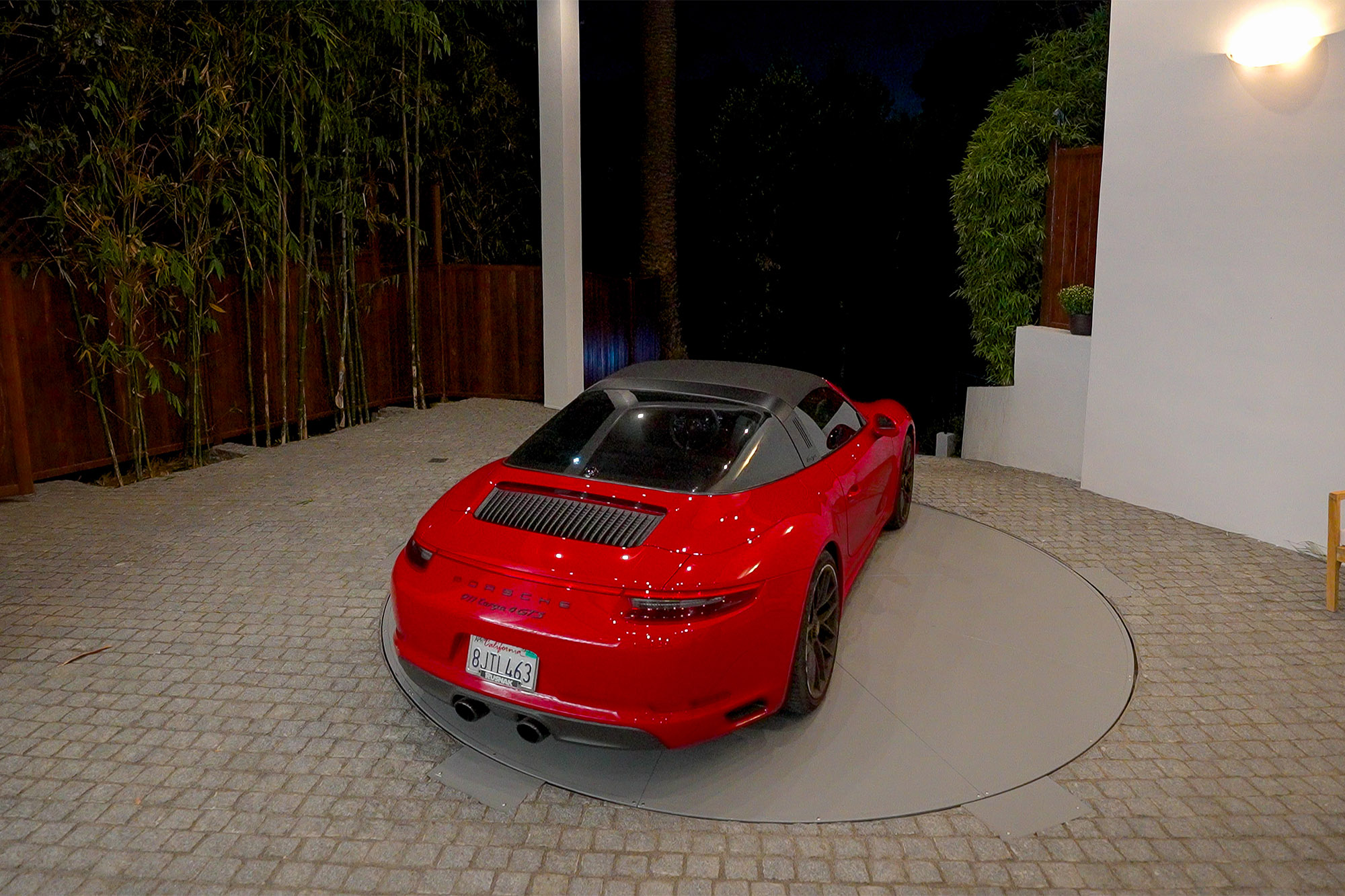 A red sports car turns on a turntable in a driveway.