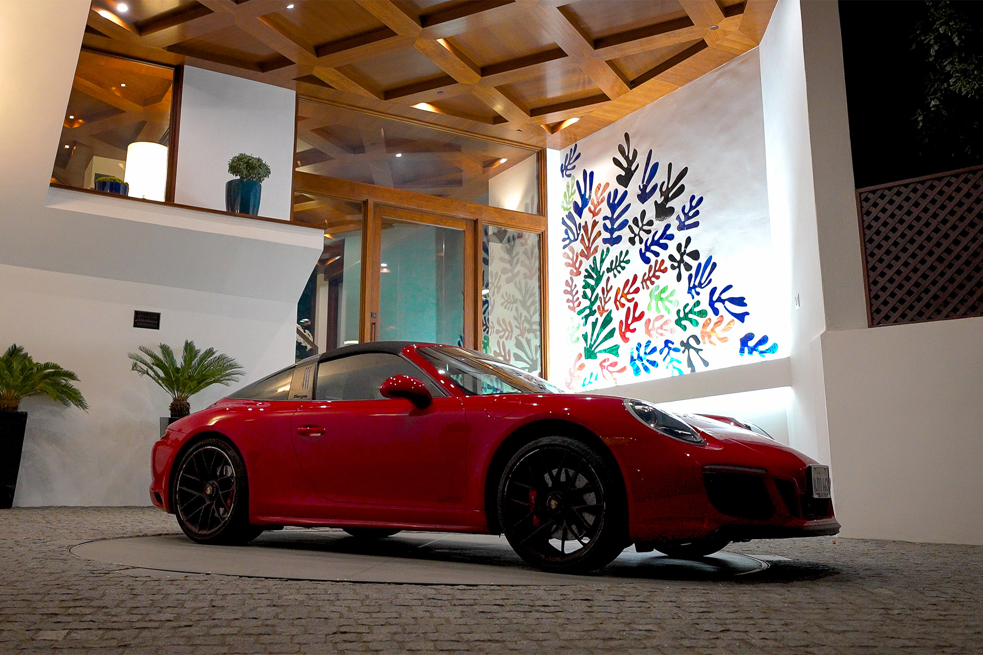 A red sports car turns on a turntable in a driveway.