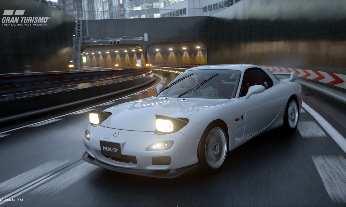 A Mazda Rx 7 drifts in the rain on a Tokyo Expressway in Gran Turismo 7.