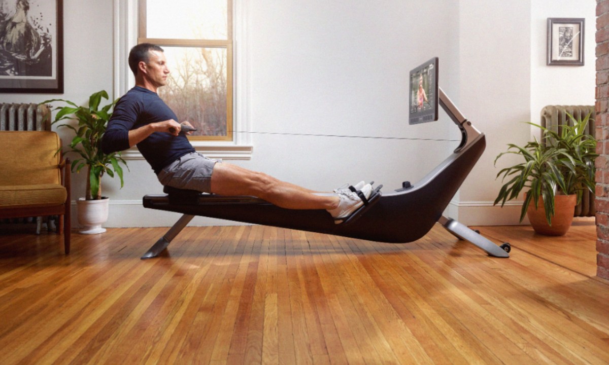 Man using a Hydrow Connected Rower in a room with a hardwood floor.