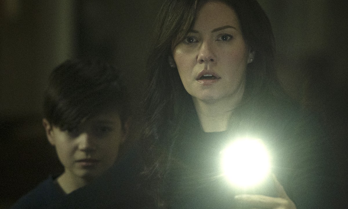 Keira holds a light up with Steven standing behind her in a scene from The Cellar.