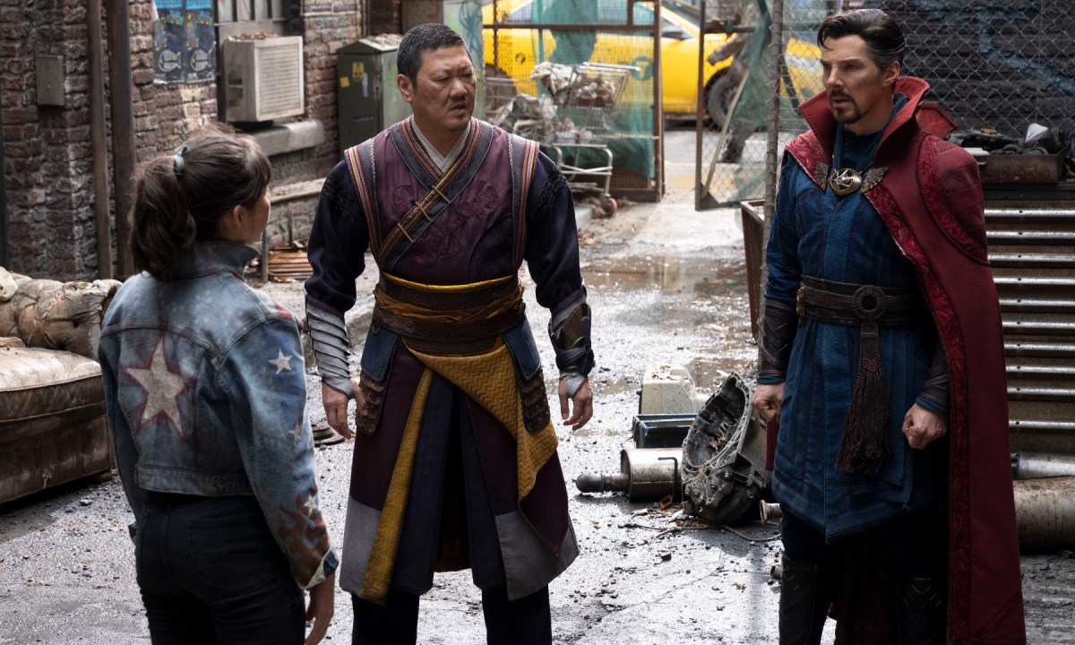 Xochitl Gomez, Benedict Wong, and Benedict Cumberbatch stand on a street in a scene from Doctor Strange in the Multiverse of Madness.
