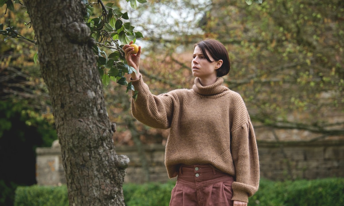 Jessie Buckley picks an apple from a tree in a scene from Men.