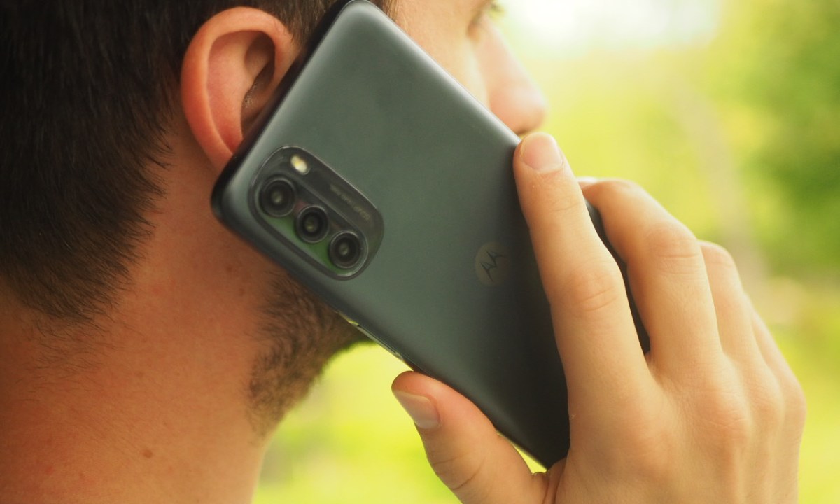 A person holding a Moto G 5G smartphone up to their ear