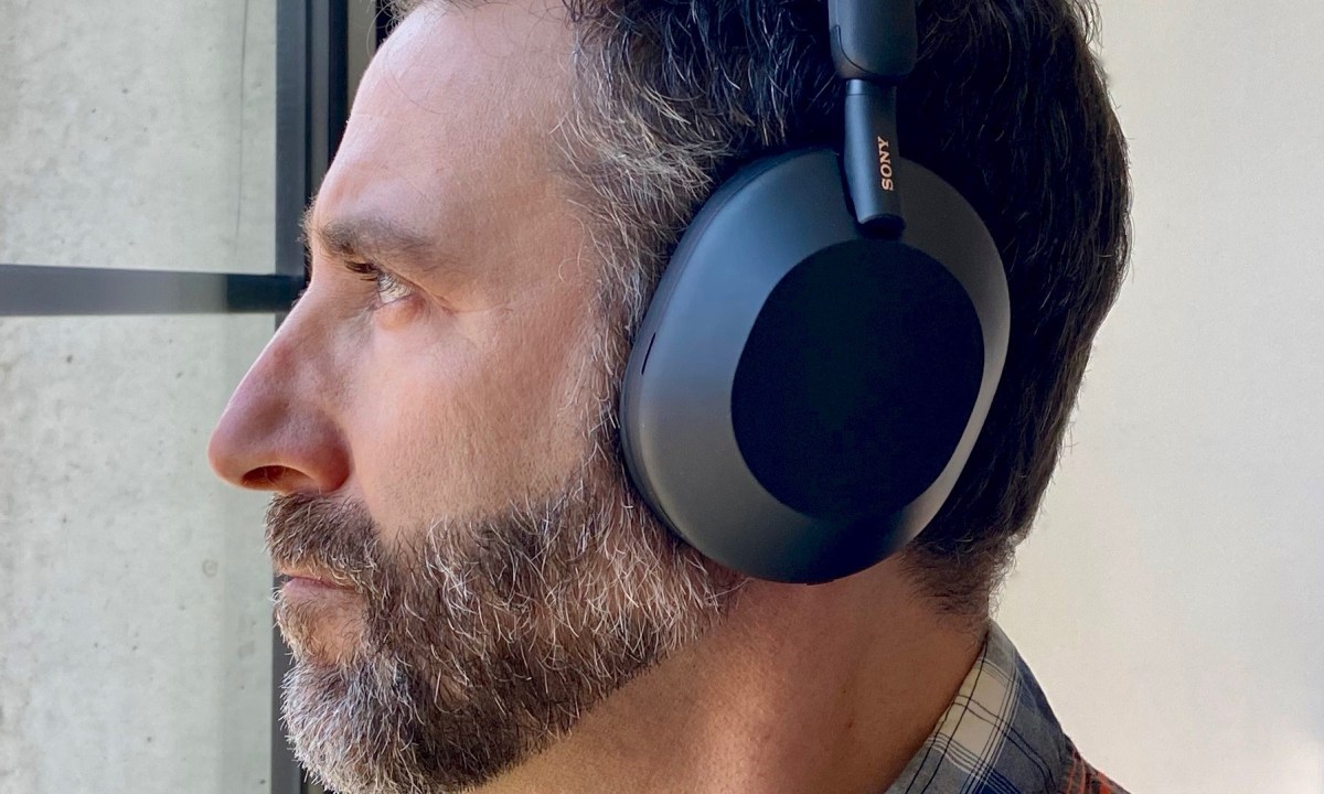 Side view of man wearing Sony WH-1000XM5 wireless headphones.