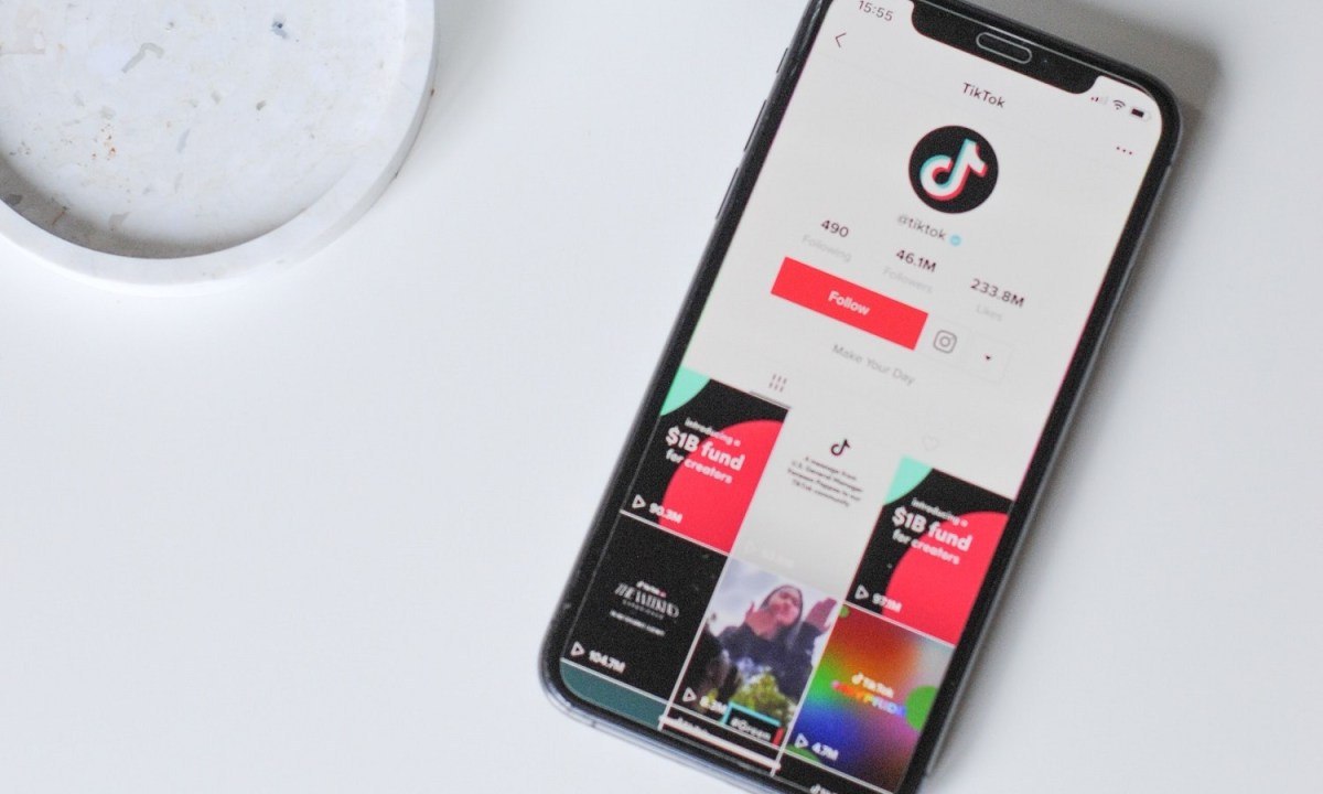 The TikTok app on a smartphone's screen. The smartphone is sitting on a white table.