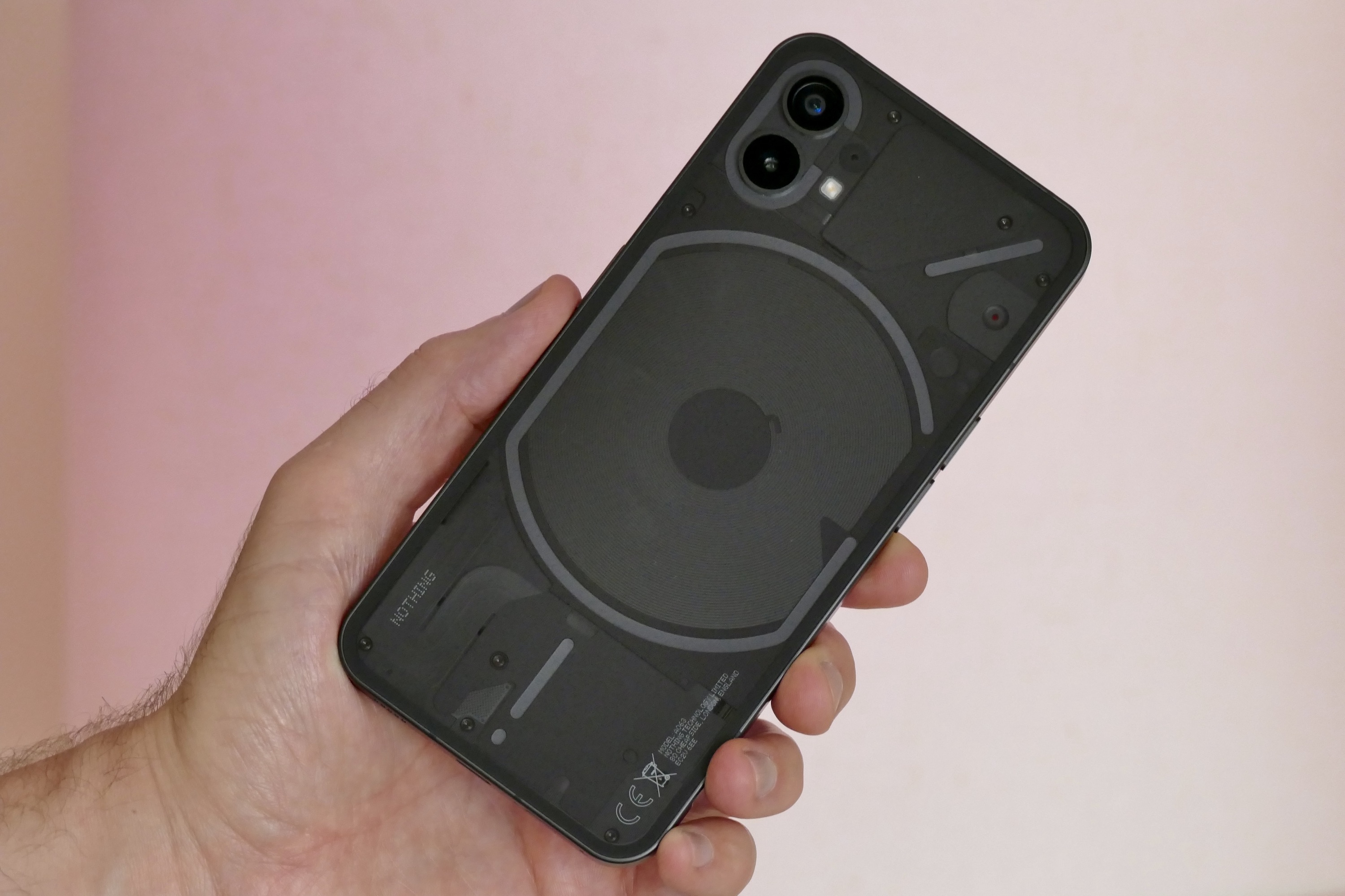 The Nothing Phone 1 held in a mans hand, seen from the back.