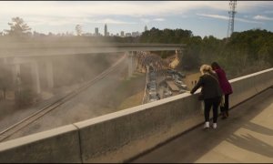 Two women stand on an overpass and watch zombies walk towards them in a scene from Tales of The Walking Dead.