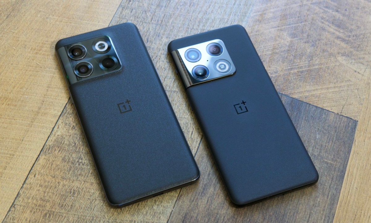 The OnePlus 10T and OnePlus 10 Pro lying a wood desk next to each other.