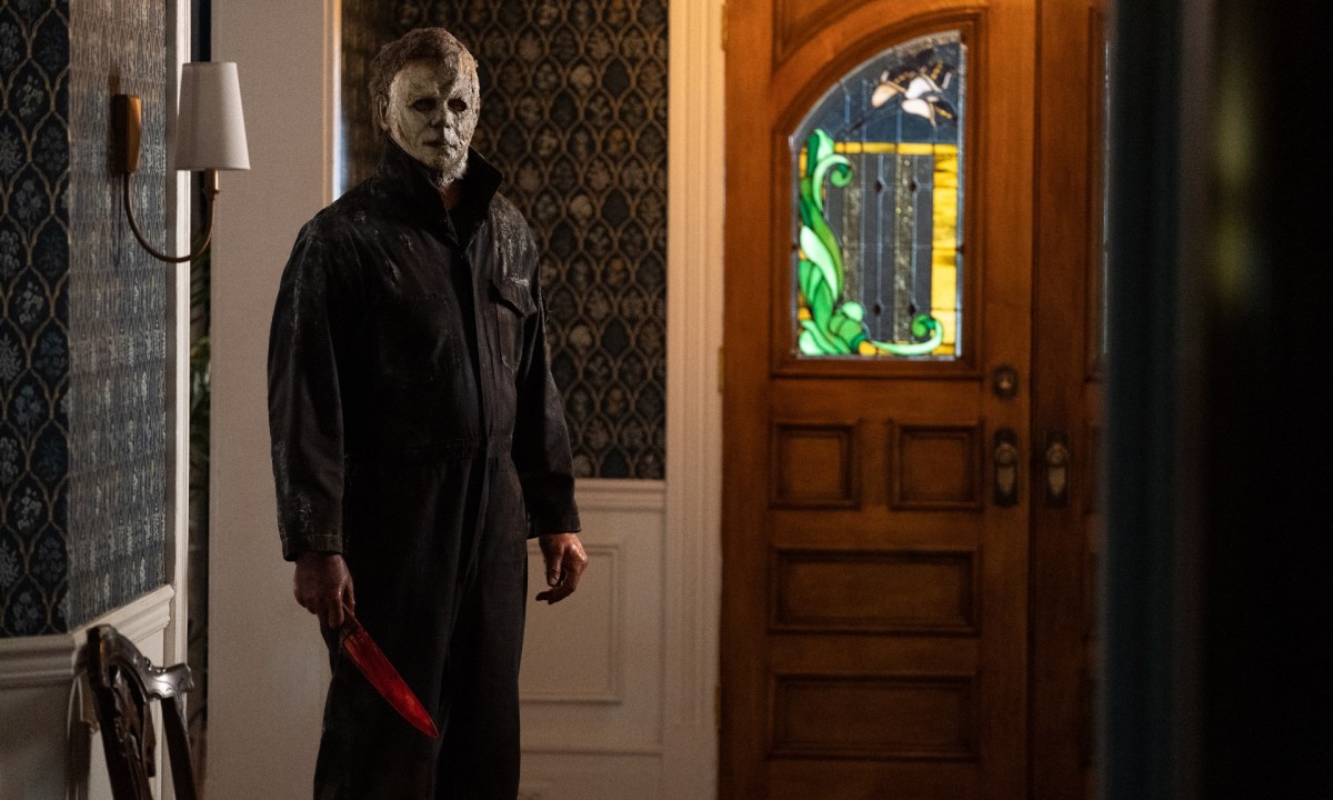 Michael Myers stares at the camera from the hallway of a house in a scene from Halloween Ends.