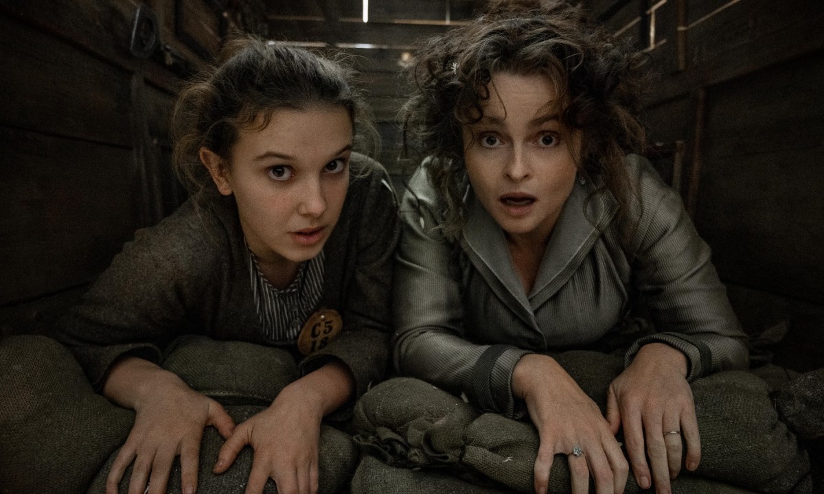 Millie Bobby Brown and Helena Bonham Carter hide under floorboards in a scene from Enola Holmes 2.