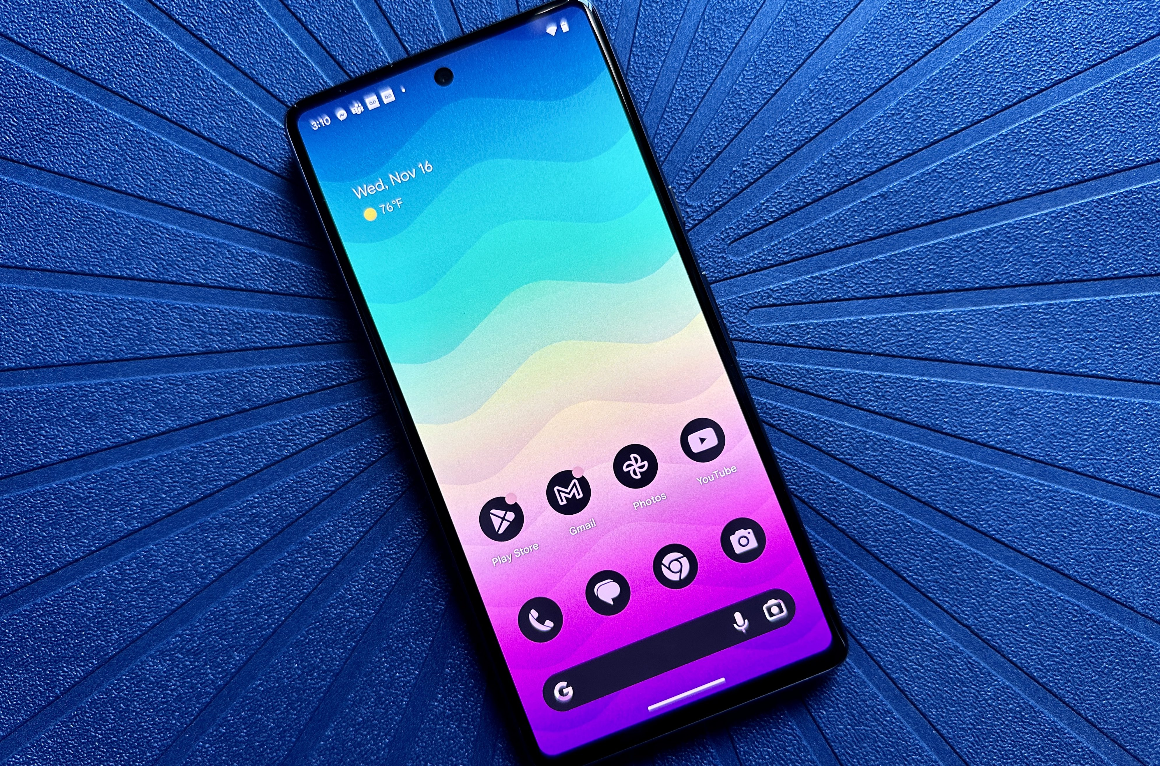 Google Pixel 7 rainbow gradient home screen on a blue placemat