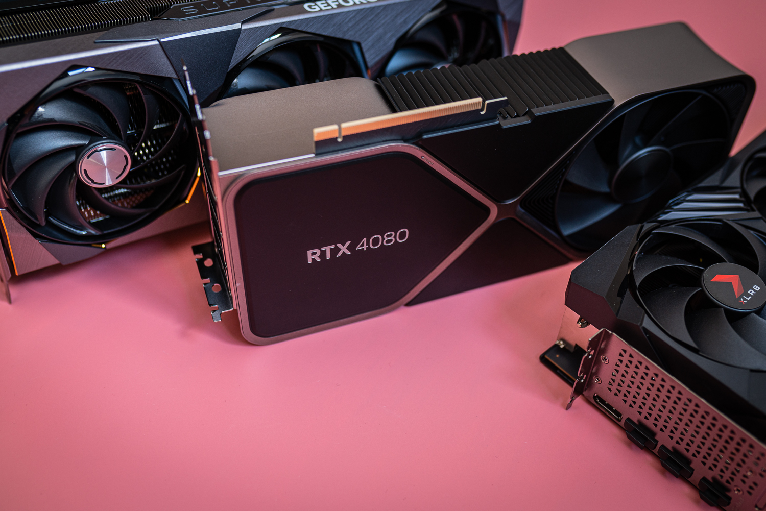 Three RTX 4080 cards sitting on a pink background.