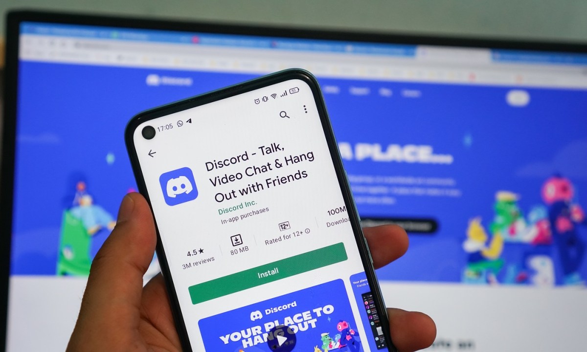 A person holding a smartphone with the Discord app displayed.