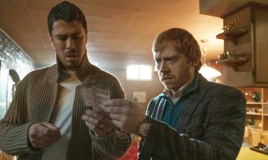Two men look at a piece of paper in Servant.