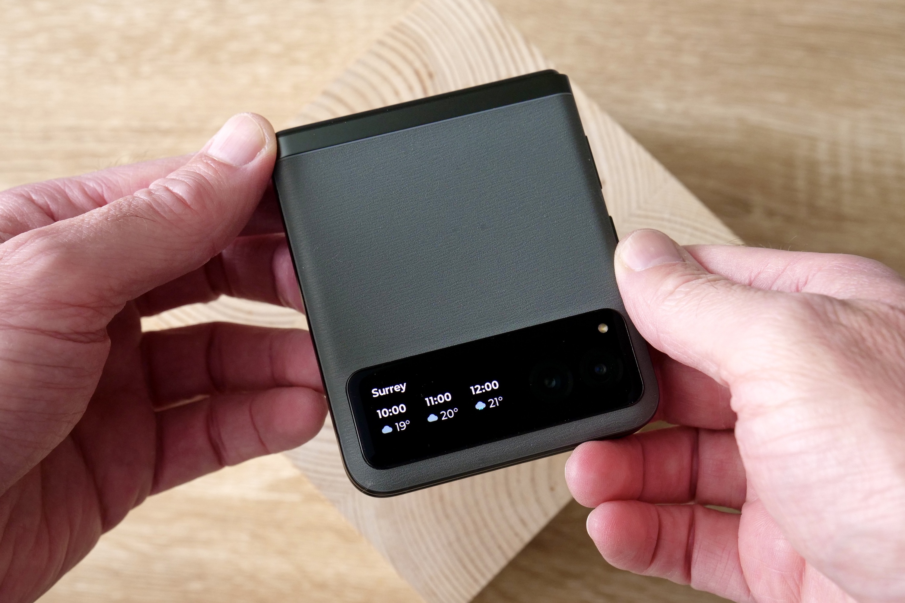 A person holding the Motorola Razr 40, showing the weather widget.