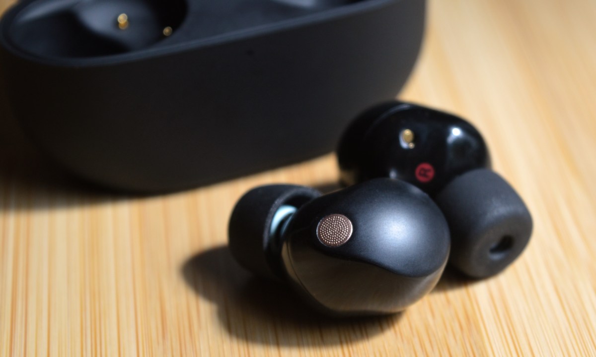 Sony WF-1000XM5 two earbuds sitting in front of charging case.