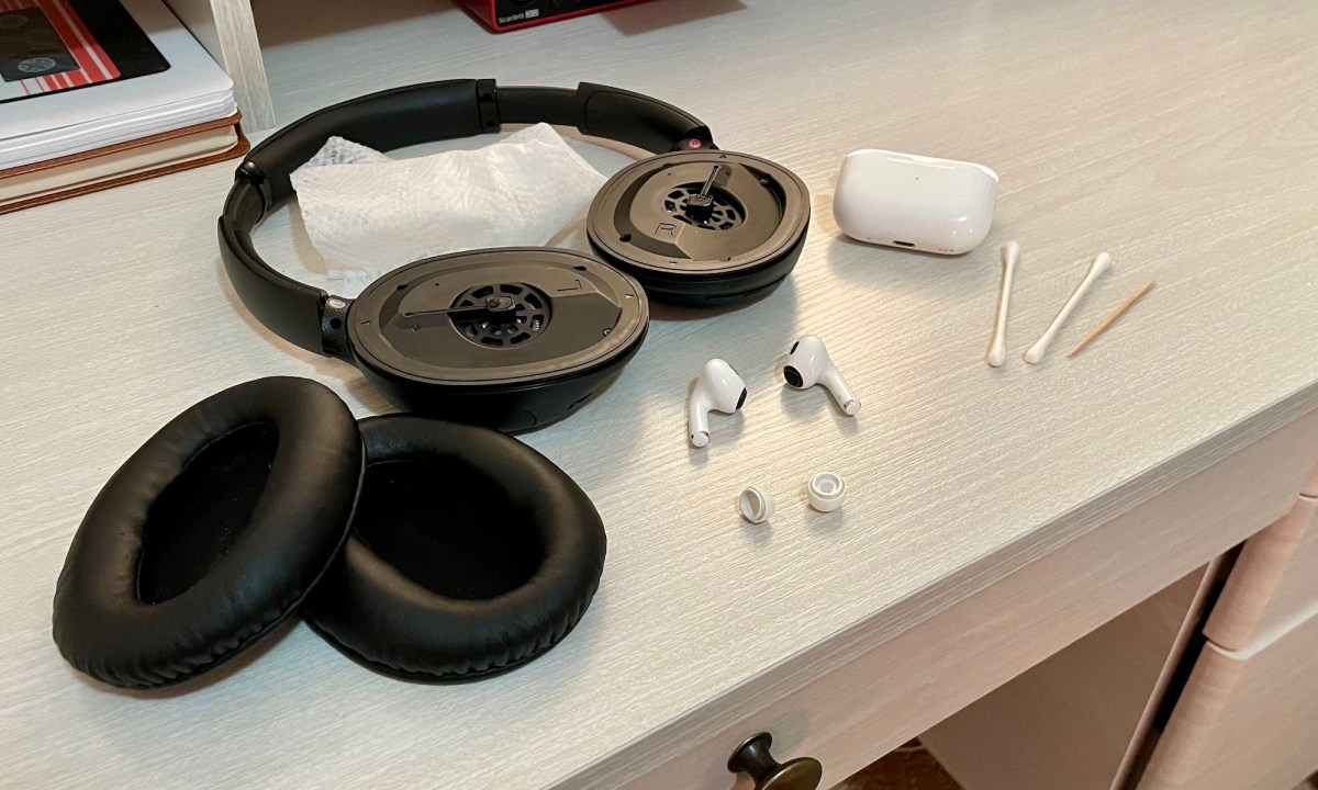Headphones, earbuds, and cleaning materials on a desk.