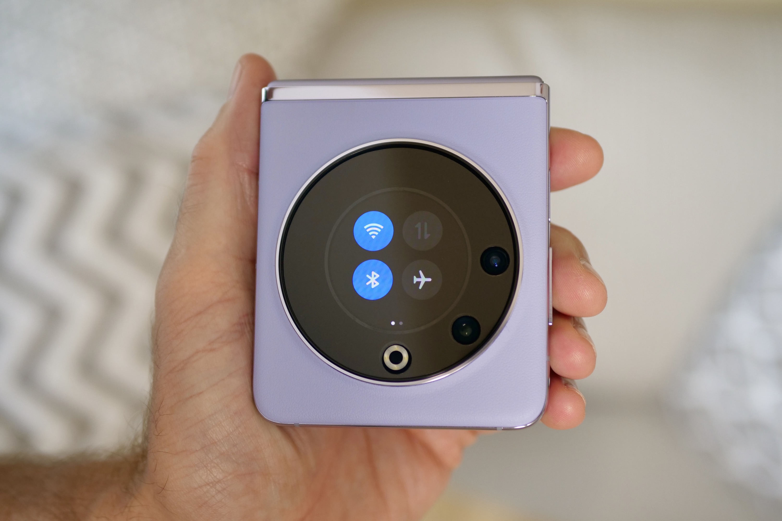 A person holding the closed Tecno Phantom V Flip, showing the Quick Settings.