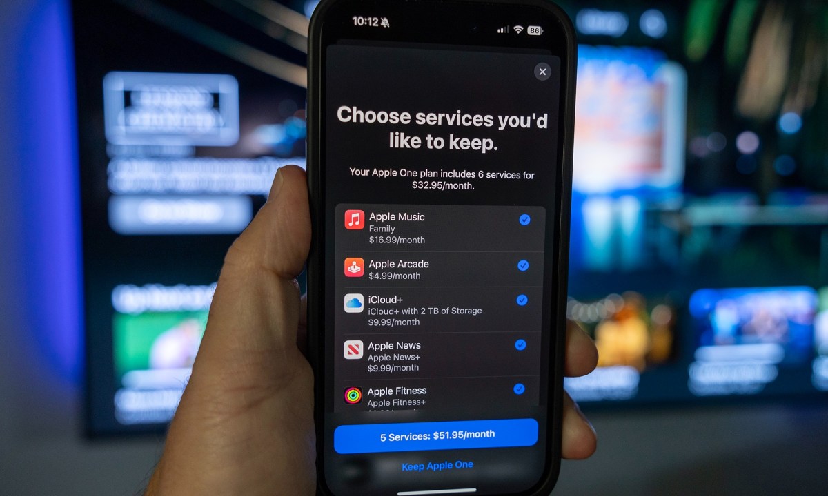 A hand holding an iPhone with the Apple TV+ and other services in a menu.