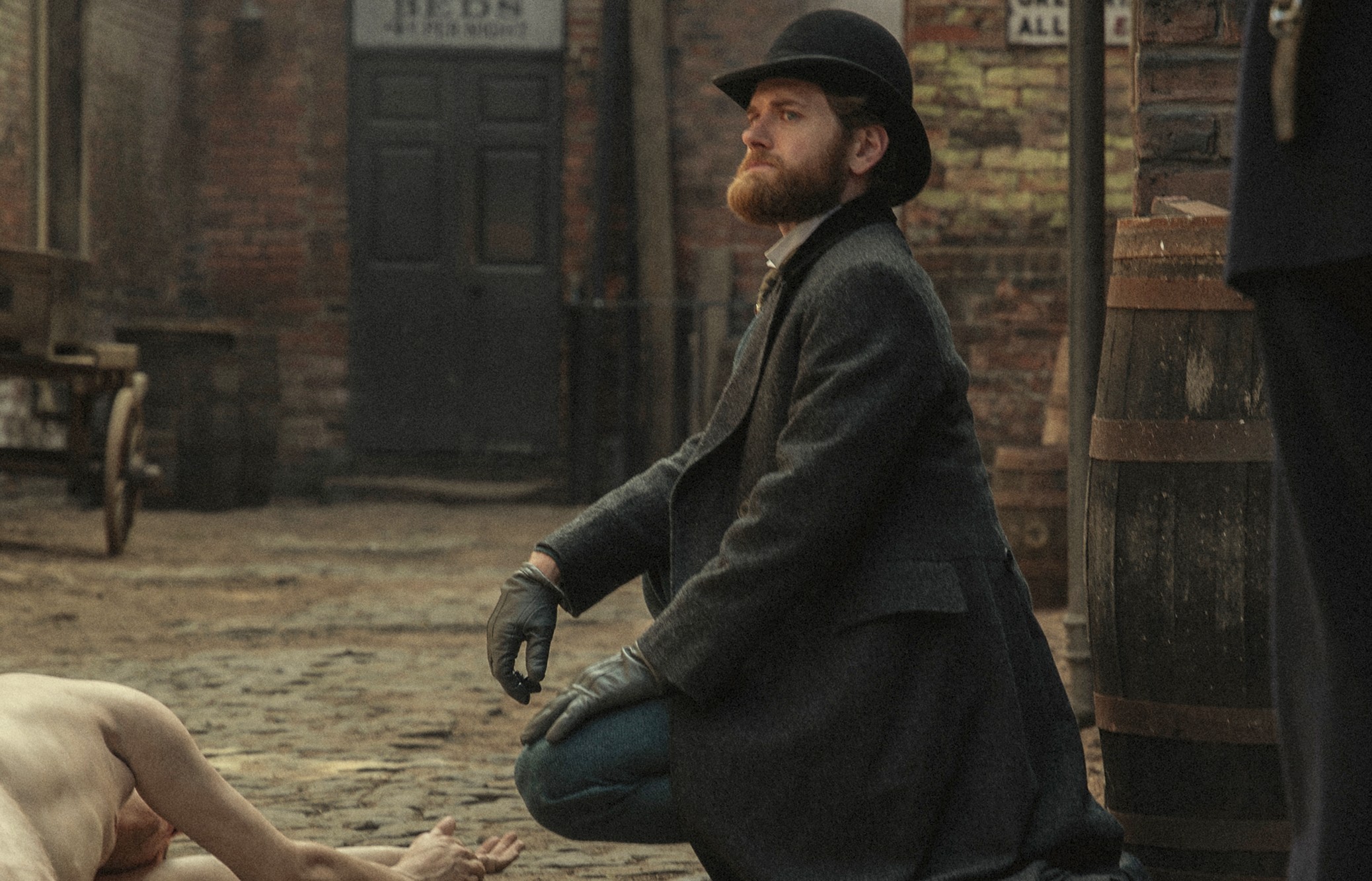 A man bends down to look at a dead body in Bodies.