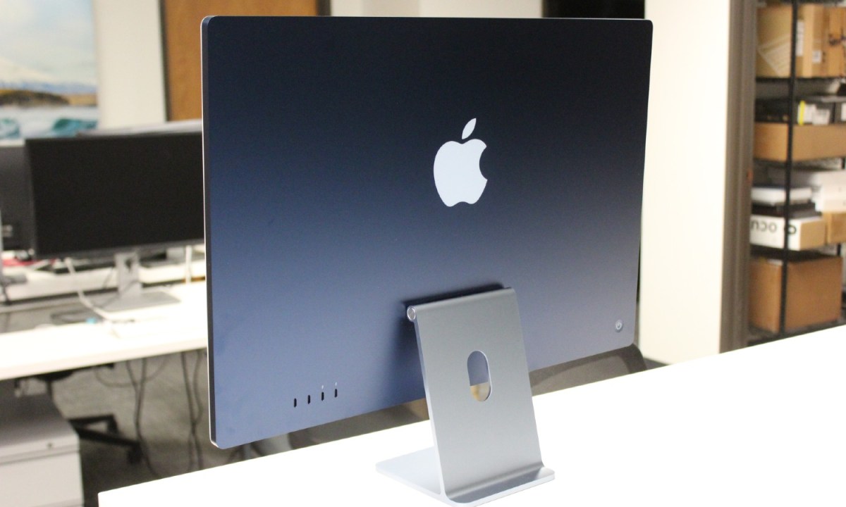 The back of a blue iMac on a white desk.