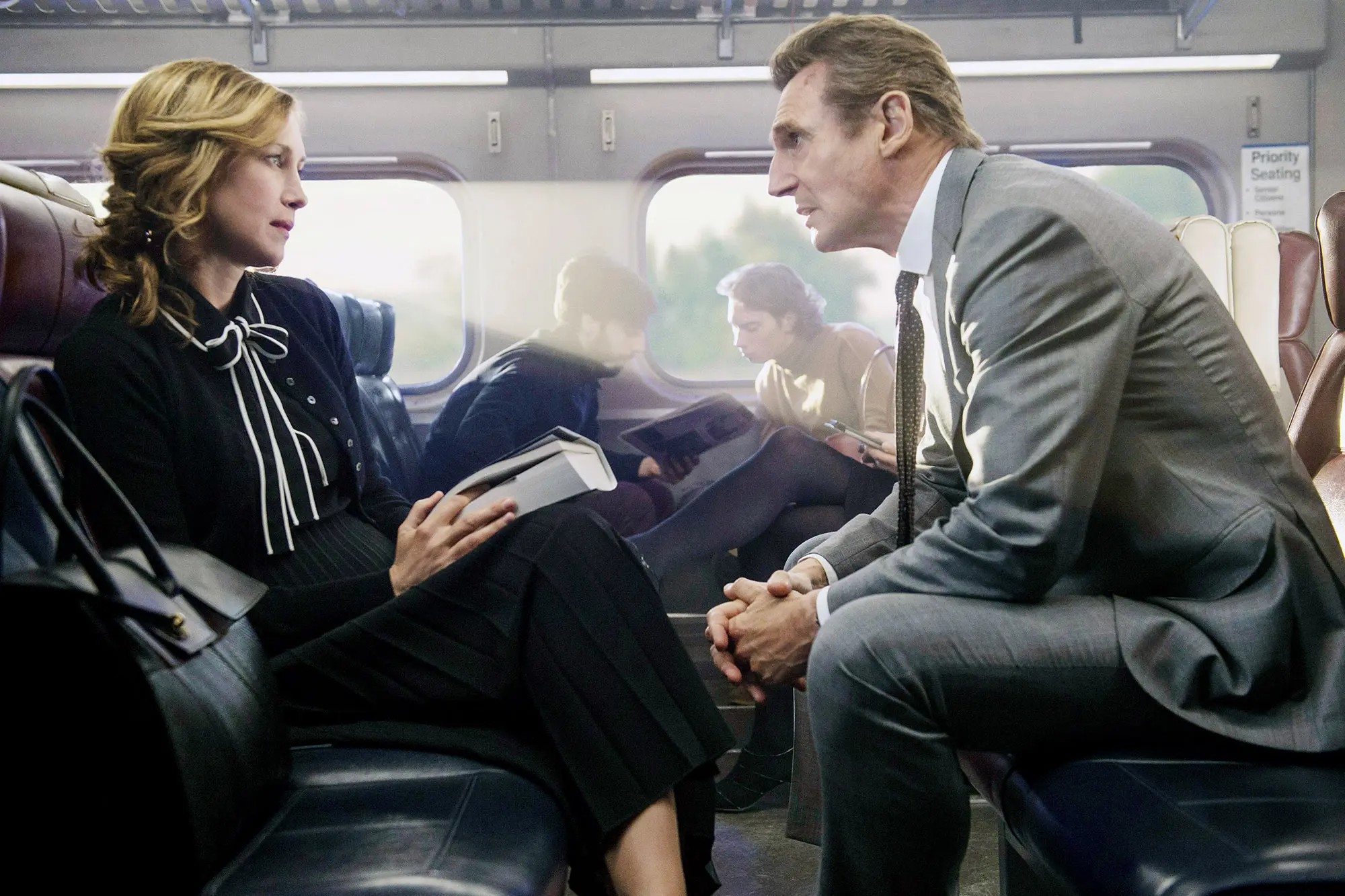 A man and a woman sit on a train in The Commuter.