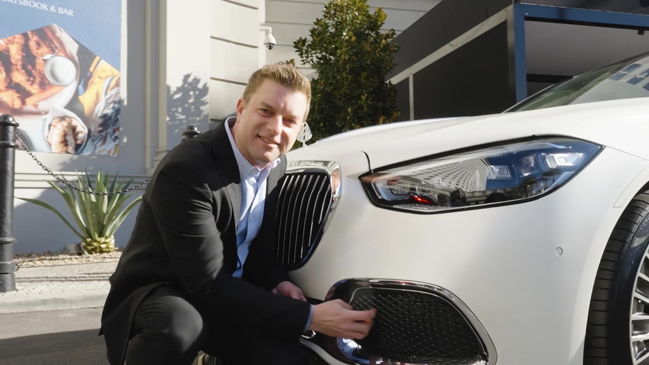 A man kneeling by a Mayback car that features Dolby atmos FlexConnect at CES 2024.