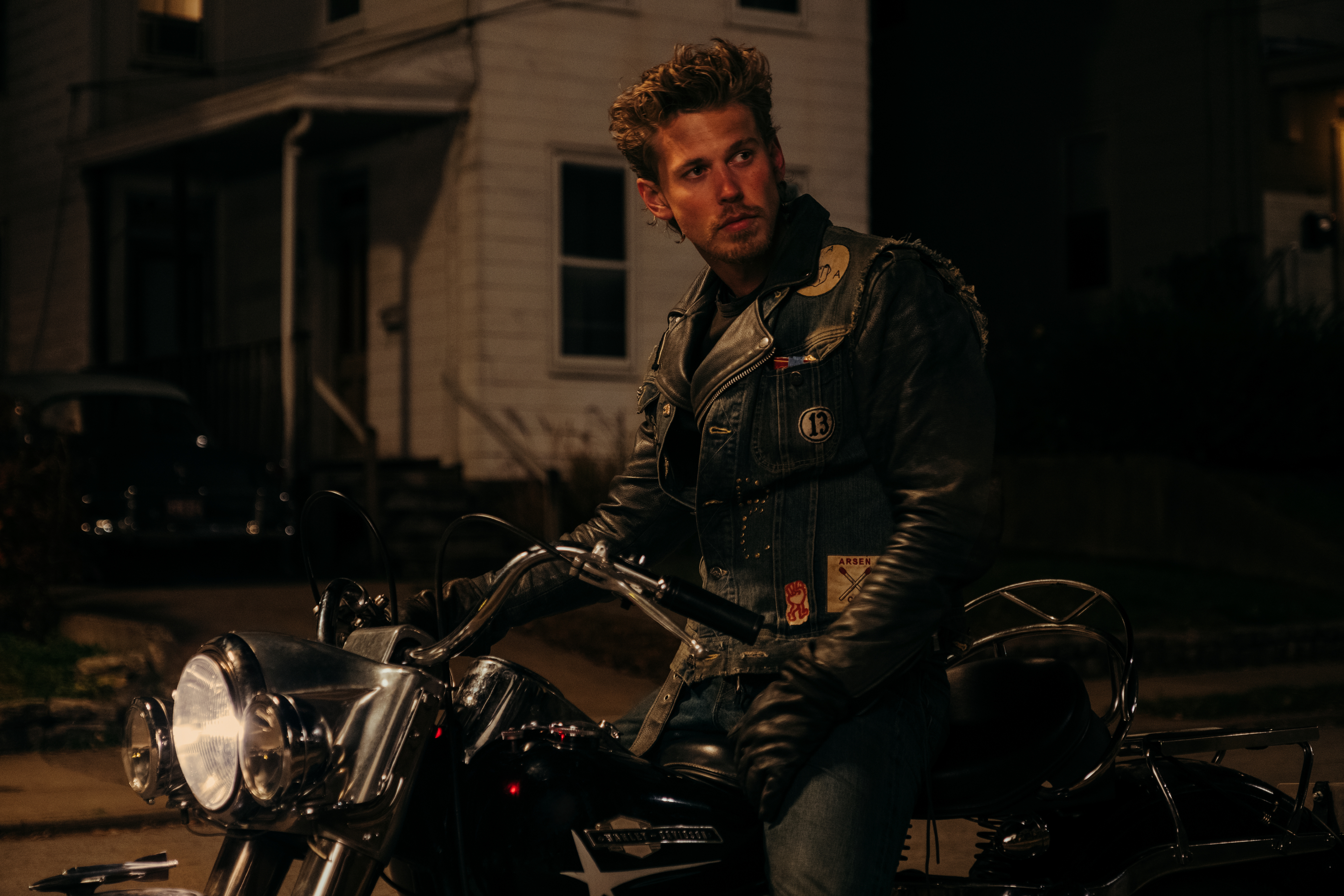 Austin Butler sits on a motorcycle at night in The Bikeriders.