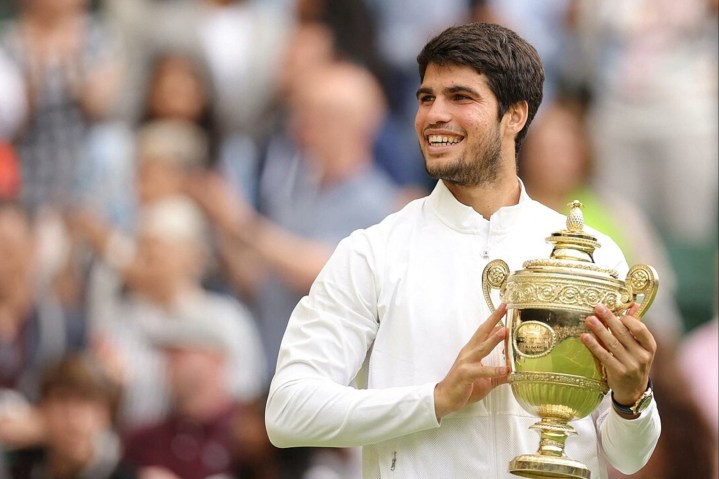 Carlos Alcaraz holds a trophy at Wimbledon.
