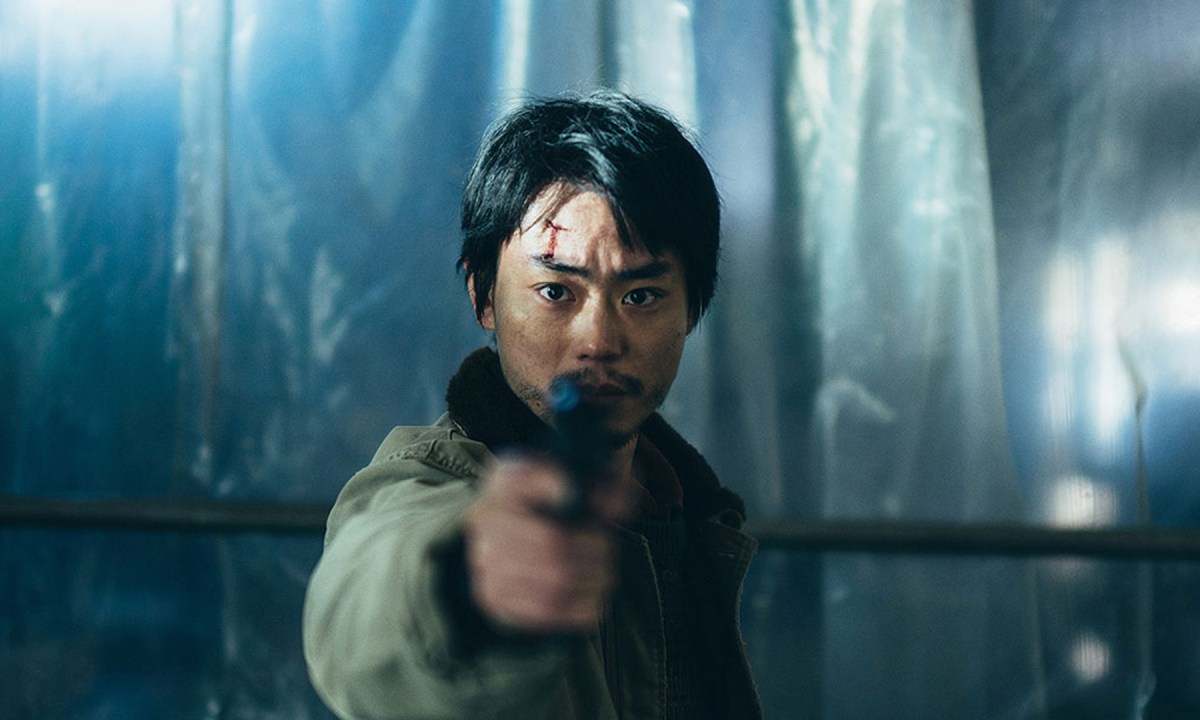 Masaki Suda aims his gun at the camera in a still from the movie Cloud.