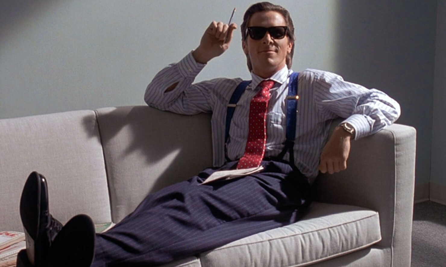 A man sits on a couch in American Psycho.
