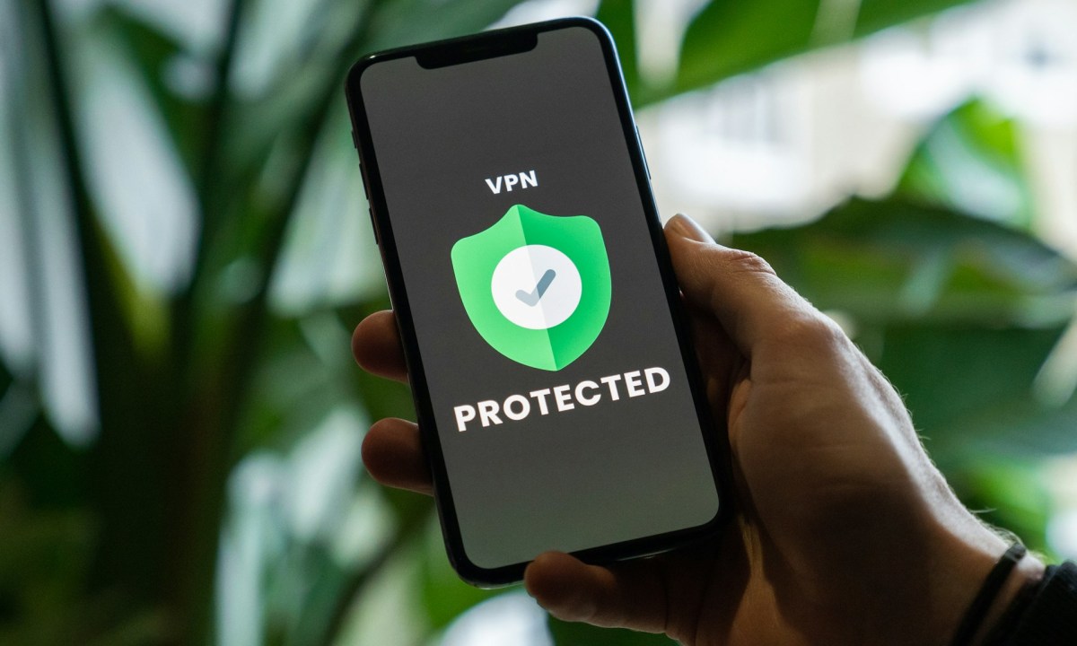 iPhone with VPN service enabled in hand over a blurred background