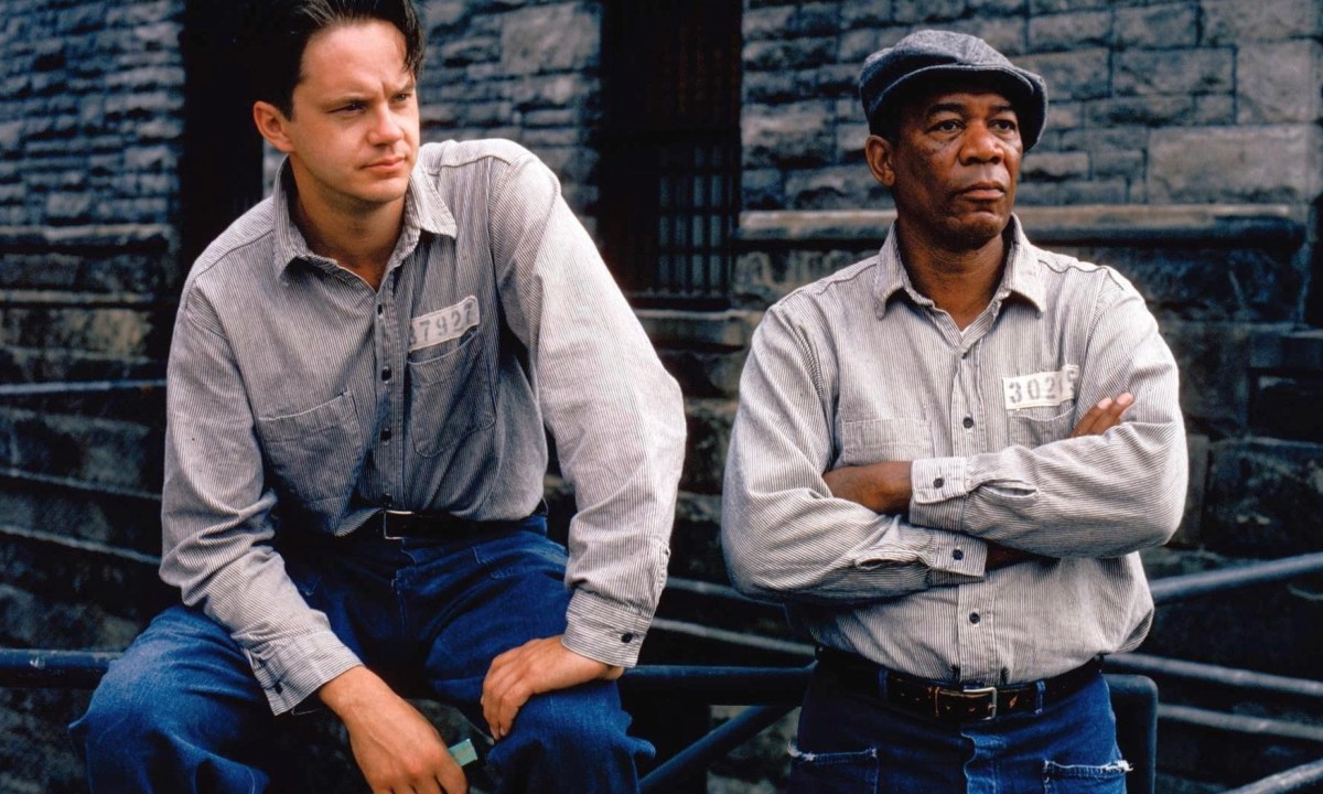 Two prisoners sit down next to each other on a bench.