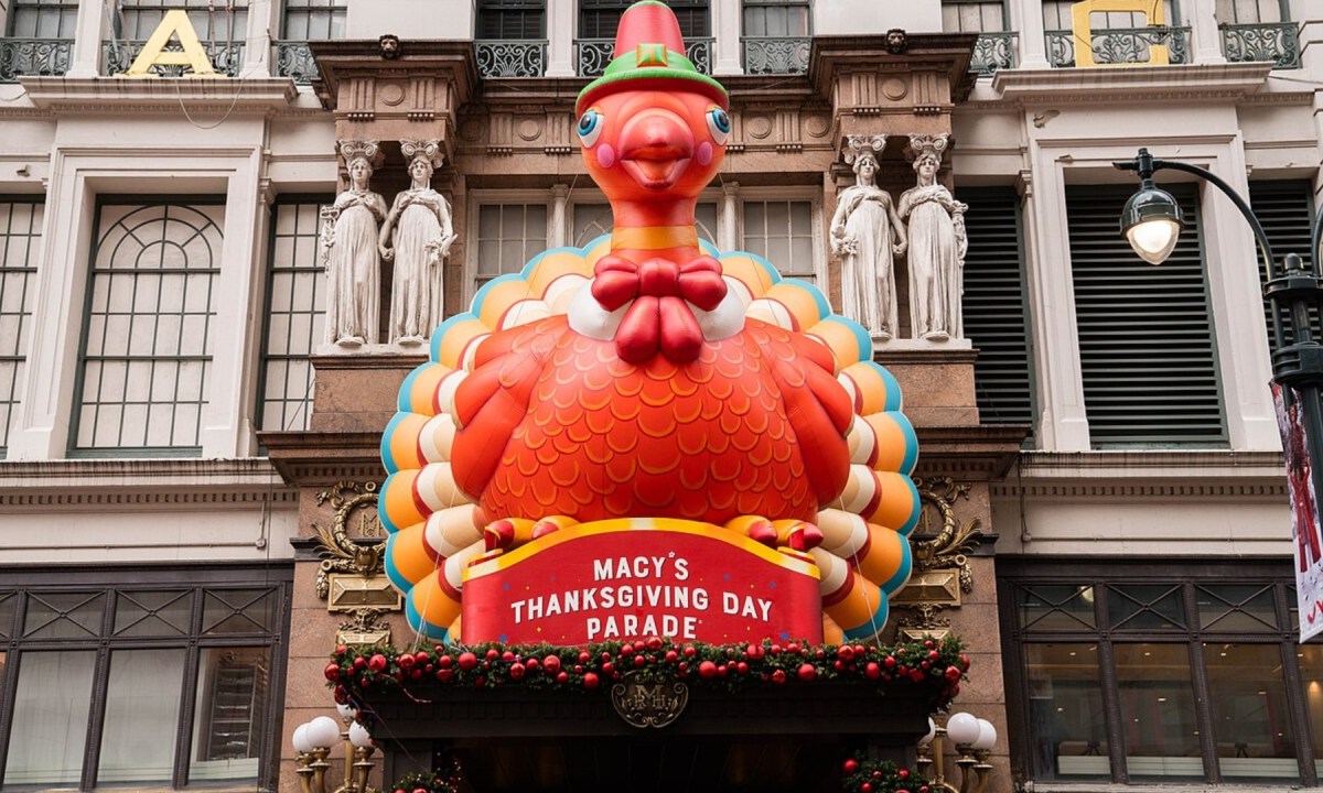 An inflatable turkey stands above a buildingsign.