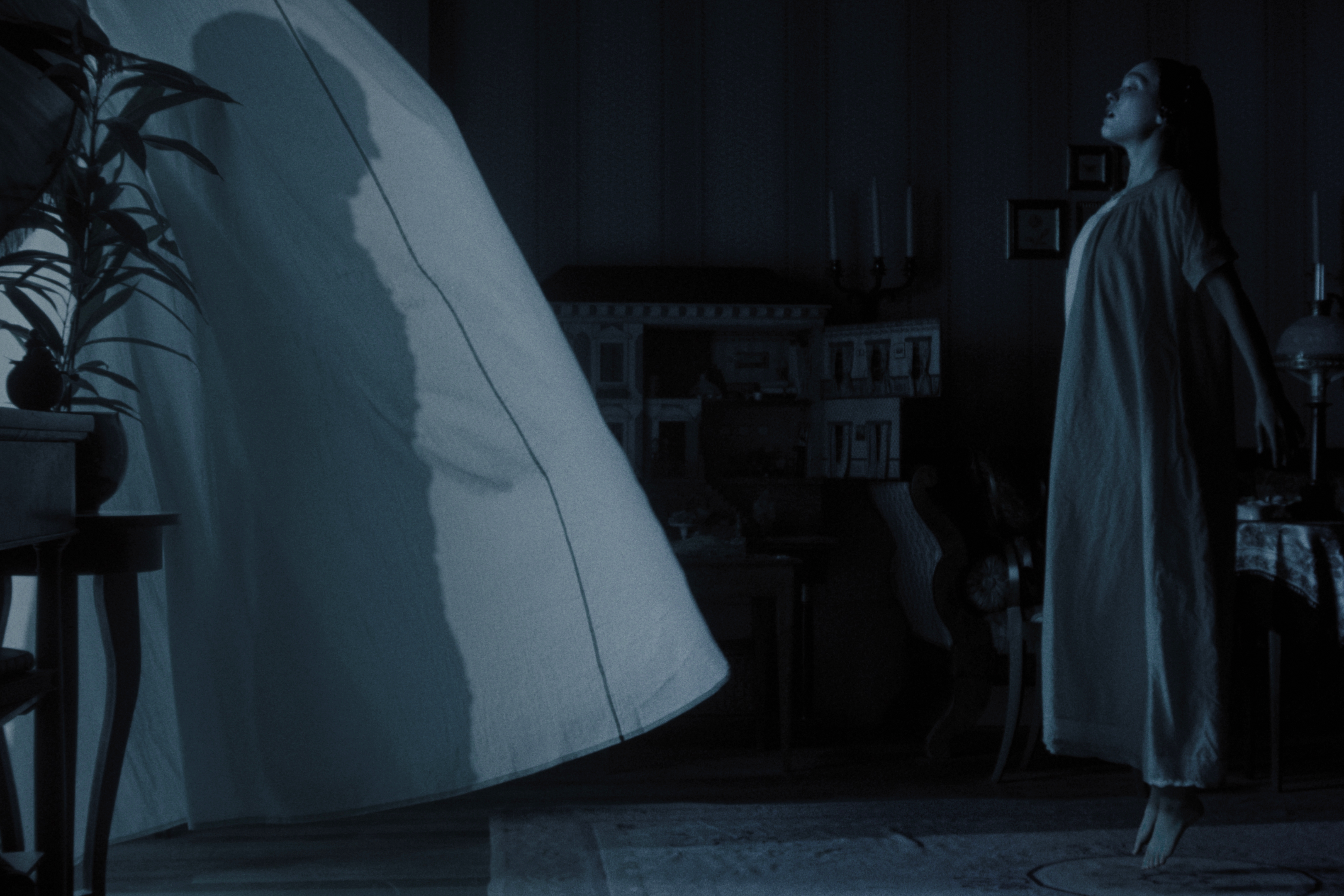 Lily-Rose Depp floats in front of billowing window curtains in "Nosferatu."