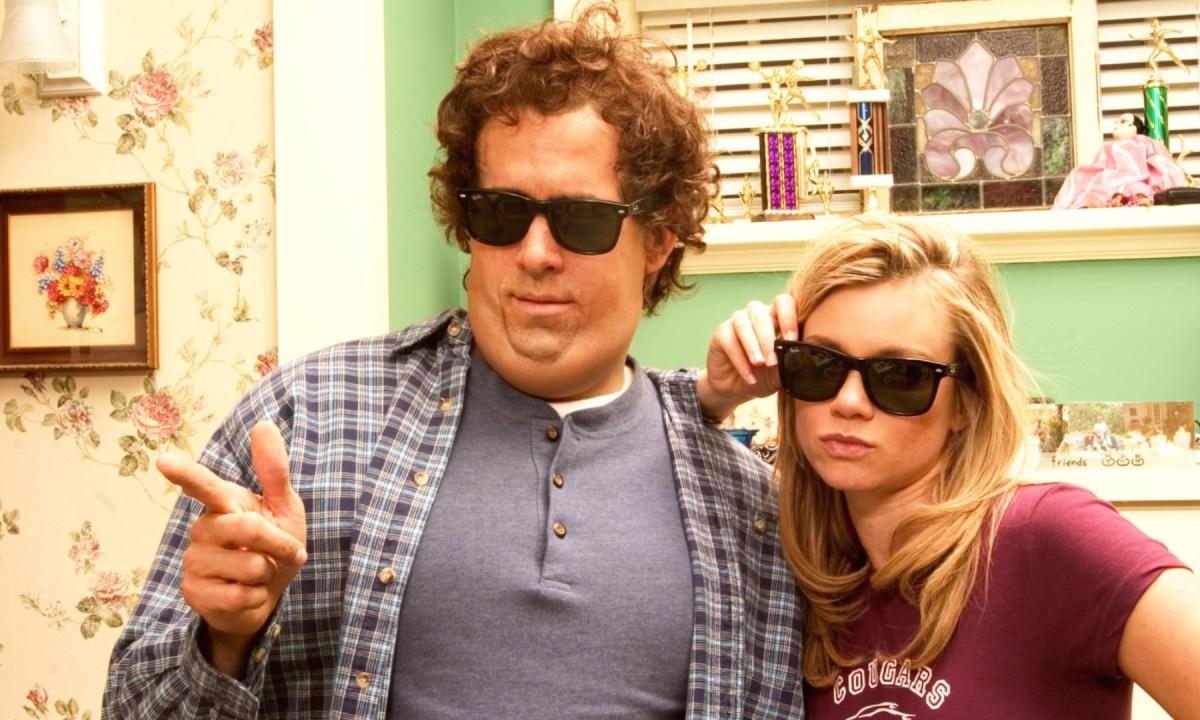 A man points his thumb as he stands next to a girl in Just Friends.