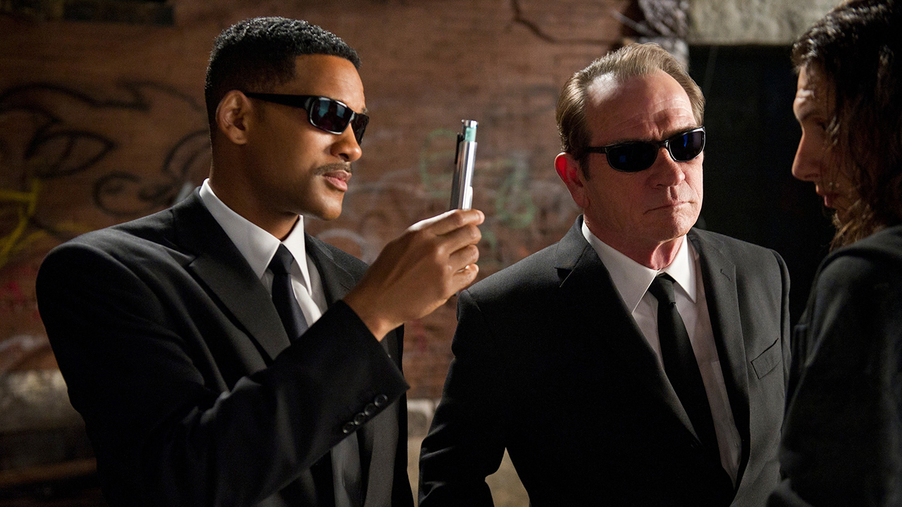Will Smith and Timmy Lee Jones wearing sunglasses and suits, Smith holding up a neuralyzer in Men in Black.