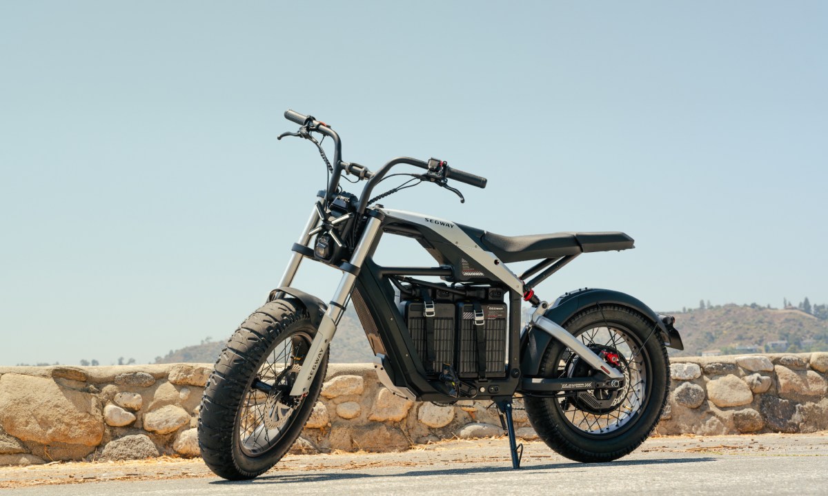 Segway Xyber e-Bike parked by a rock wall bordering a beach.