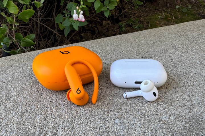 The Apple AirPods Pro 2 and Beats Powerbeats Pro 2 cases and earbuds next to one another on a stone step.