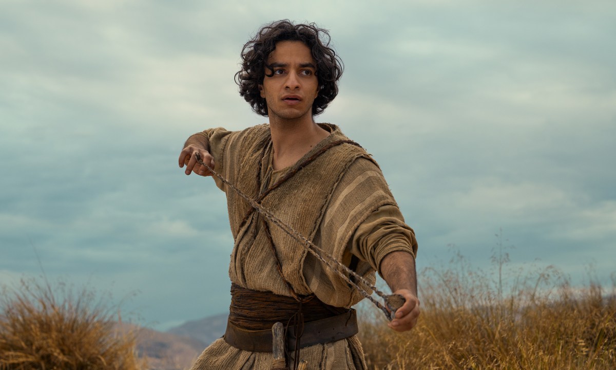 A young man with curly hair holds out a slingshot in House of David.
