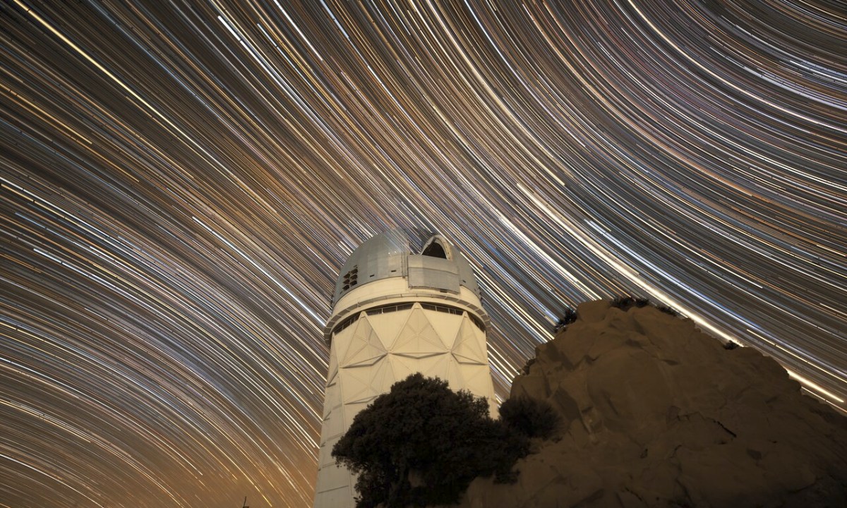 The U.S. National Science Foundation Nicholas U. Mayall 4-meter Telescope at Kitt Peak National Observatory (KPNO), a Program of NSF NOIRLab, beneath streaking star trails, created by long-exposure photography.