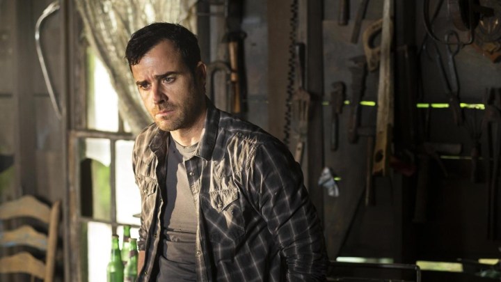 A man stands by a window in a plaid shirt looking worried in The Leftovers.